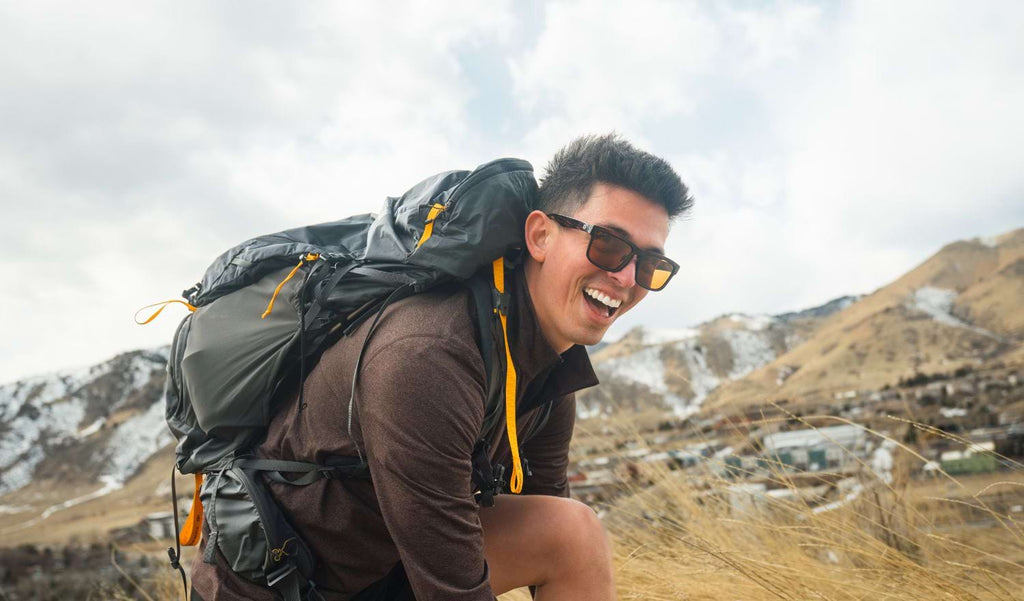Man hiking wearing Optic Nerve Mashup sunglasses with a tortoise frame and brown lenses with mountains in the background