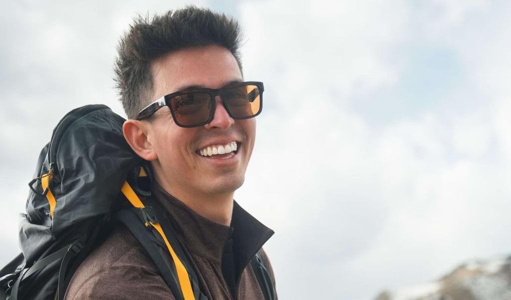 Close up of a man wearing Optic Nerve Mashup sunglasses with a tortoise frame and brown lenses with a blurred sky background