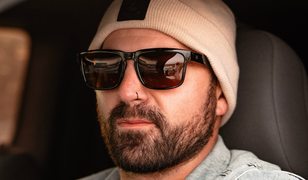 Person wearing Optic Nerve Mashup XL sunglasses with a tortoise frame and brown lenses, with a beanie in a car.