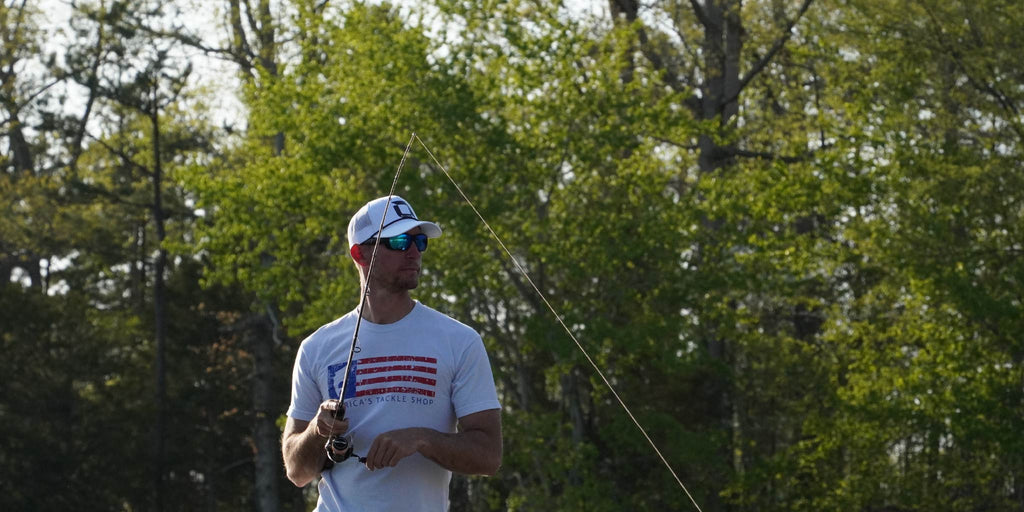 Man holding a fishing rod wearing Optic Nerve polarized sunglasses with trees in the background