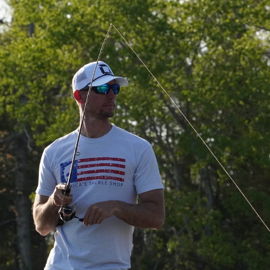 Man holding a fishing rod wearing Optic Nerve polarized sunglasses with trees in the background