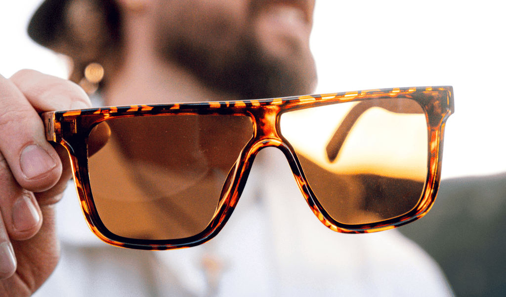 Close up of Optic Nerve Mojo Filter Wood sunglasses with tortoise frame and brown lens with blurred background