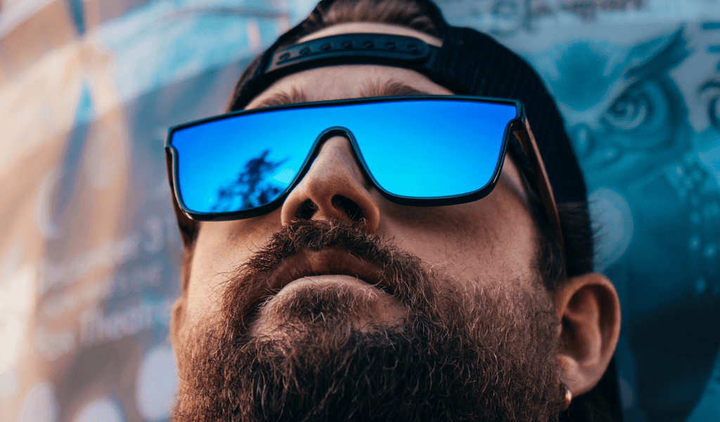 Close up  of a man wearing Optic Nerve Mojo Filter Wood sunglasses with FSC wood temples, black frame, smoke lens, and a blue mirror