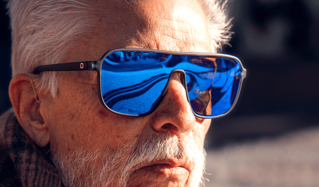 Close up of an older man wearing Optic Nerve Montrose sunglasses with a blue frame, brown lens, and a blue mirror