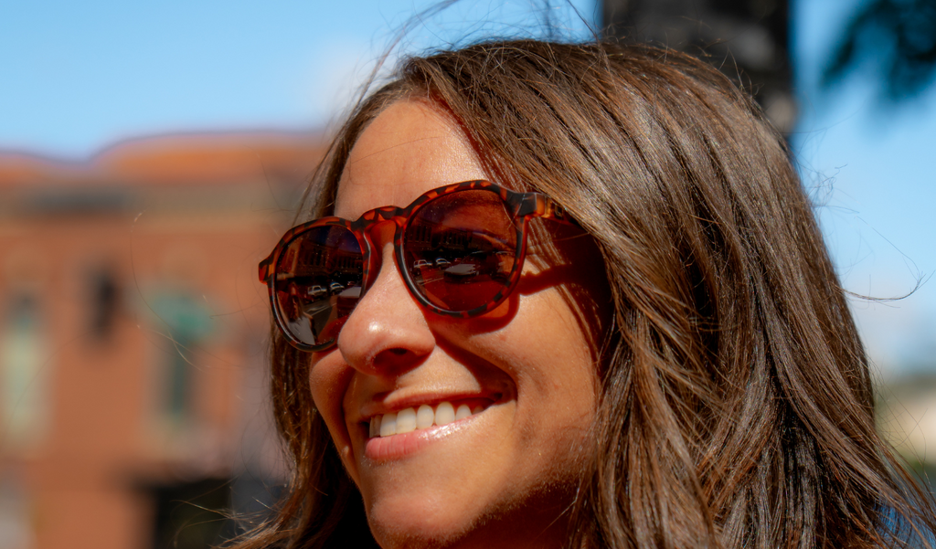 Woman wearing Optic Nerve RiNO sunglasses with a tortoise frame and brown lens with a blurred background