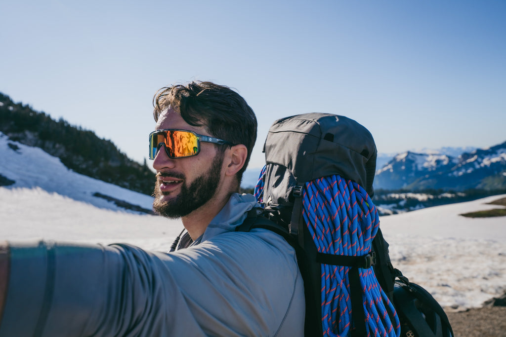 Man with a backpack and OPtic Nerve Scraggy sunglasses in a mountainous landscape