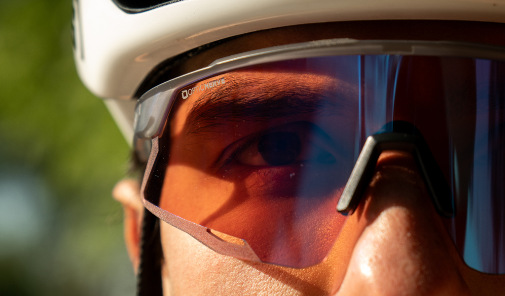 Close up of a person wearing Optic Nerve FixieAIR sunglasses with a gray frame, smoke lens, and red mirror