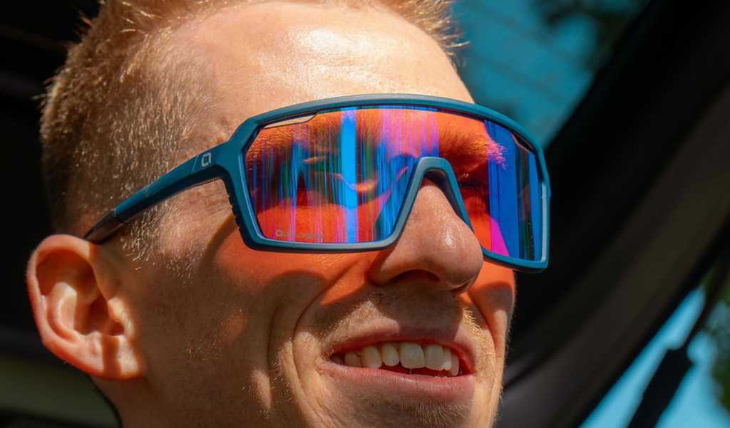 Close up of a man wearing FixiePHENOM 2.0 sunglasses with a blue frame, copper lens, and a silver mirror 