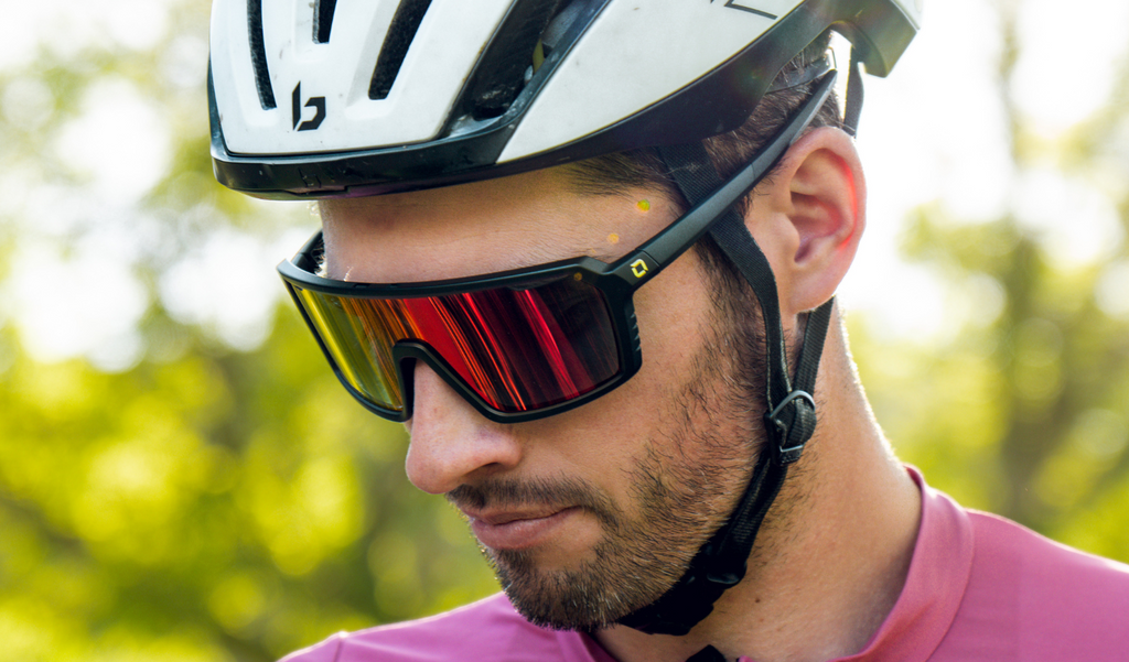 Close up of a cyclist wearing FixiePHENOM 2.0 Photochromic sunglasses with a black frame, photochromic lens, and a red mirror