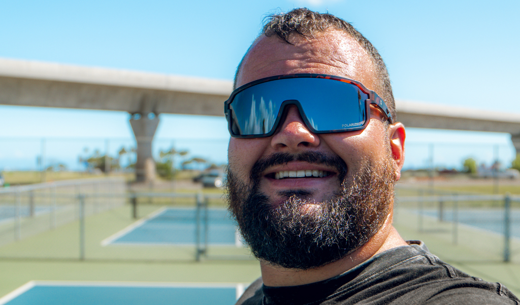 Man wearing Optic Nerve Scraggy sunglasses with a tortoise frame, smoke lens, and a silver mirror, outdoors on a clear day