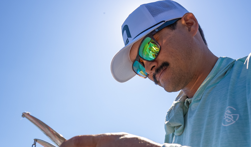 Close up of Chris Zaldain wearing an Optic Nerve cap and Optic Nerve  Zaldaingerous Rumble sunglasses with a tortoise frame, amber lens, and a green mirror with a blue sky background