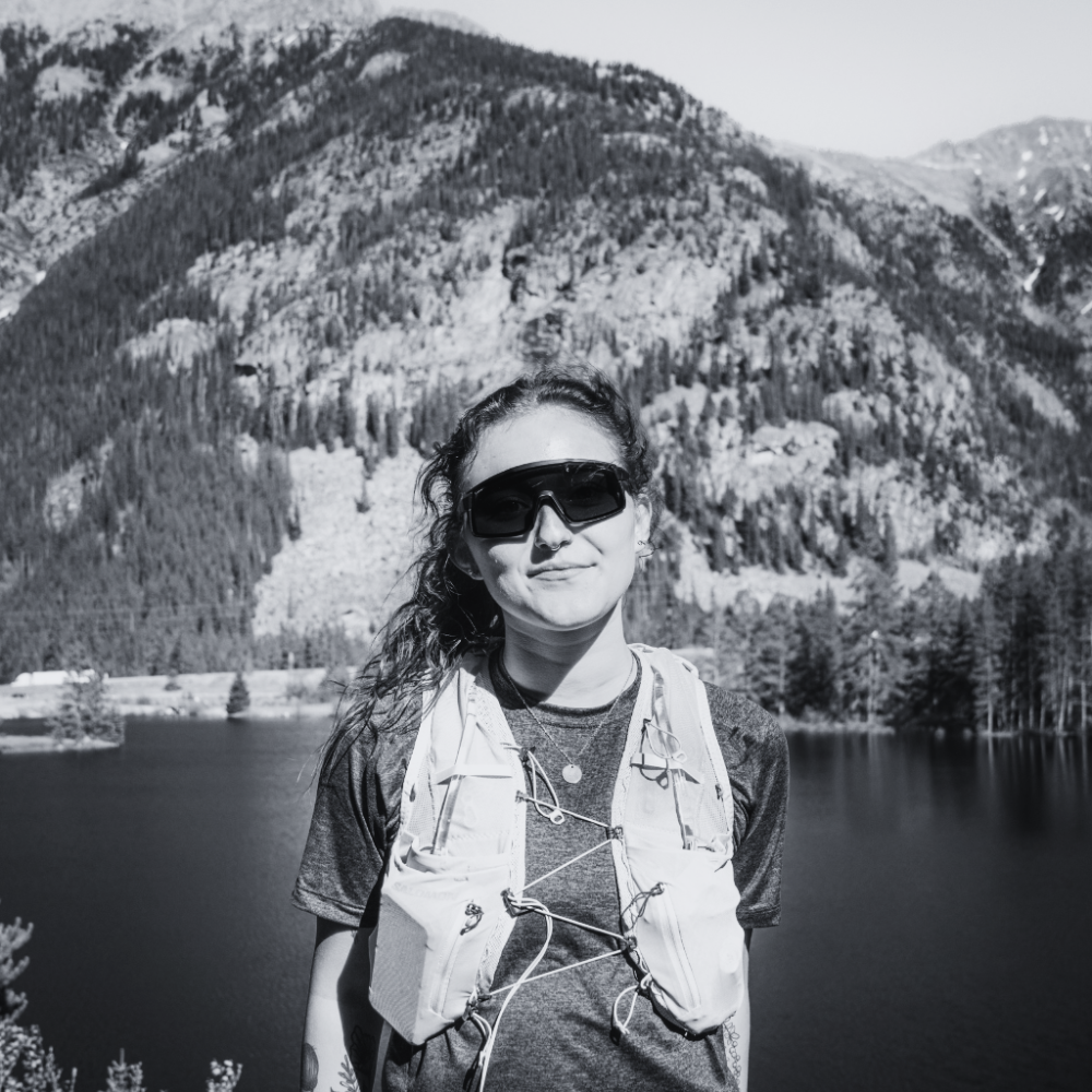 Person standing in front of a mountain lake with FixieMAX sunglasses on