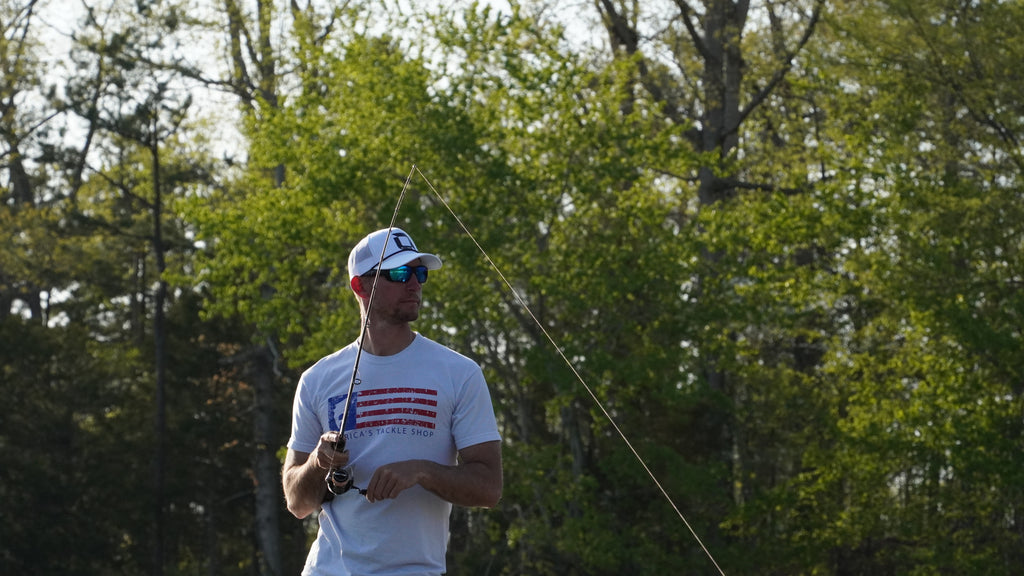 Man holding a fishing rod wearing Optic Nerve Polarized sunglasses with trees in the background