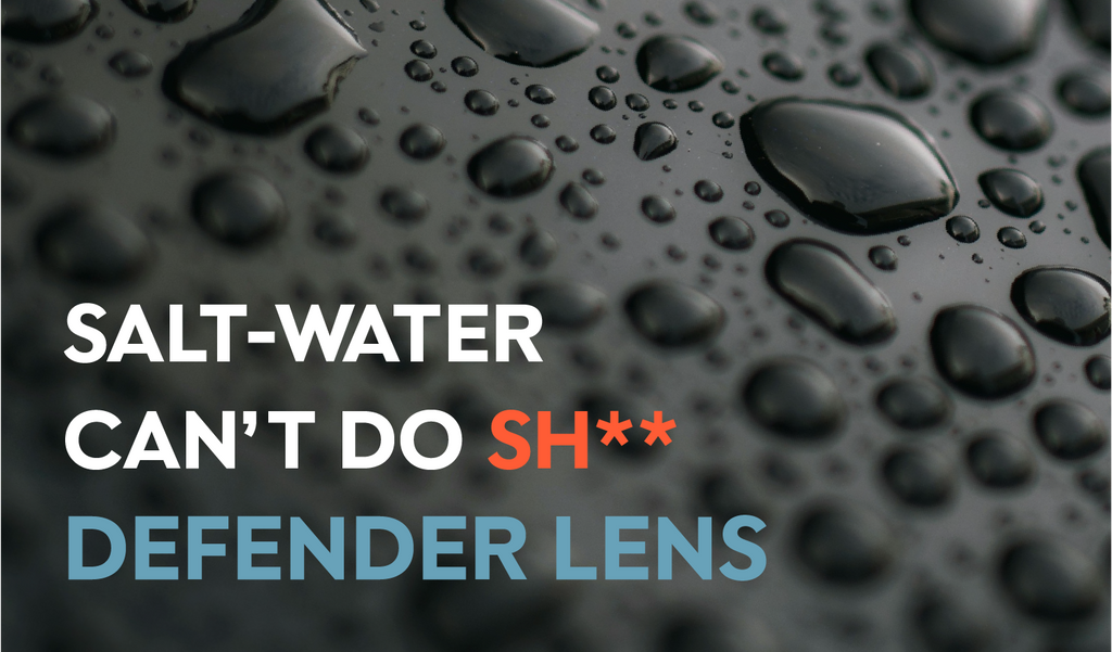 Water droplet beads on a black surface. Text on image reads "Salt-water can't do sh** Defender Lens"