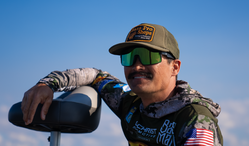 Person wearing a cap and Optic Nerve Zaldaingerous FixieMAX sunglasses with a black frame, amber lens, and a green mirror, with a clear blue sky background