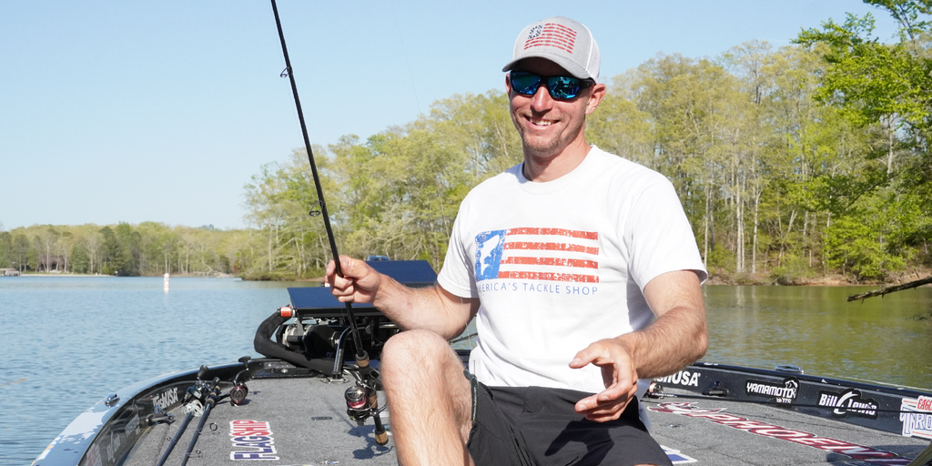 Man fishing on a boat wearing Optic Nerve sunglasses with trees and water in the background