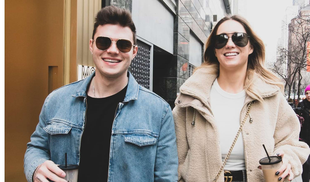 Two people wearing Optic Nerve sunglasses walking down a street with buildings in the background