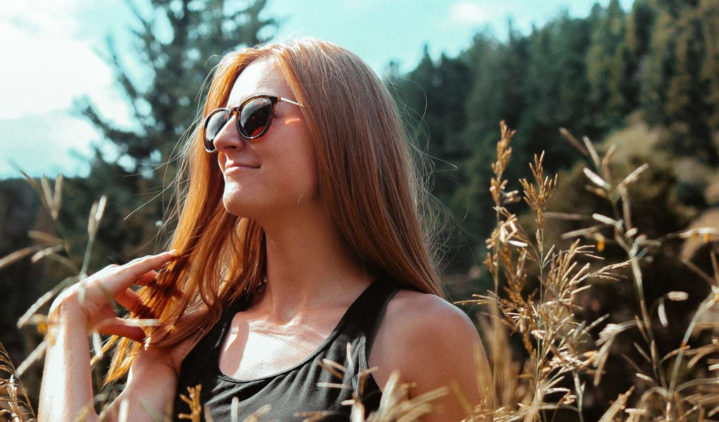 Woman wearing Optic Nerve Pizmo sunglasses with a tortoise frame and brown lenses with a natural background
