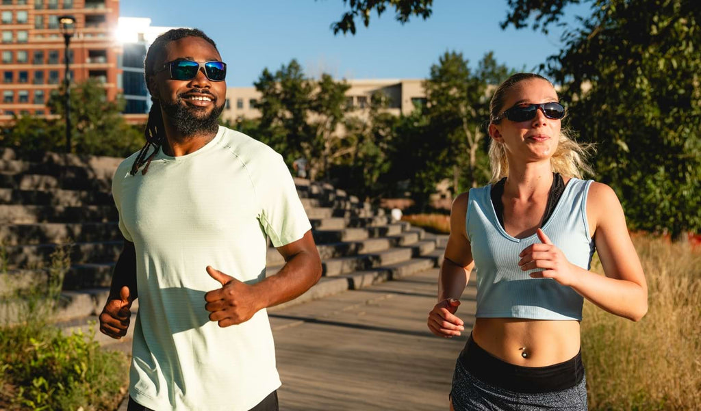 Two people running on a running path wearing Optic Nerve sunglasses